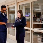 Male and female nurses comparing notes in hallway at Anderson Hospital