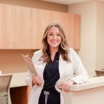 Young female nurse at Anderson Hospital, holding clipboard and smiling