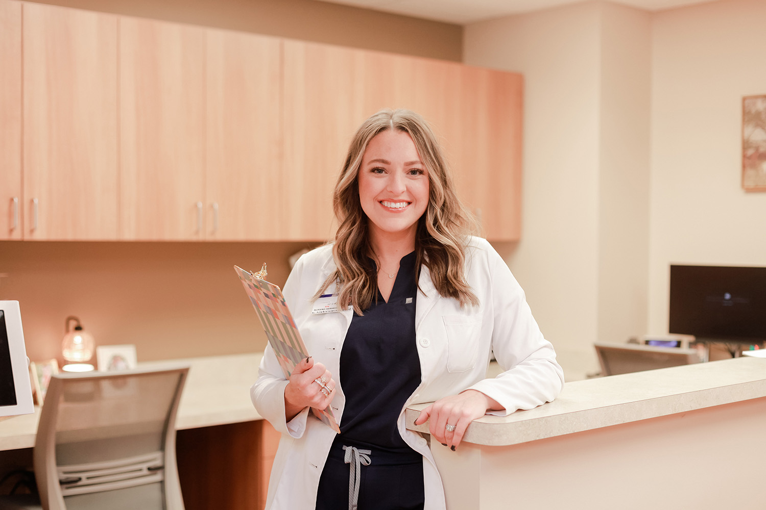 Young female nurse at Anderson Hospital, holding clipboard and smiling