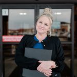 Anderson Home Health Caretaker smiling in front of hospital doors